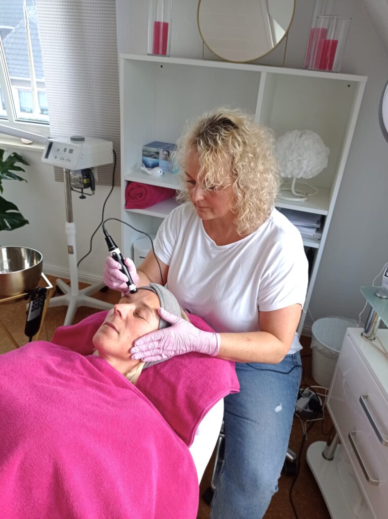 Kosmetikerin Doris führt ein Microneedling für ihre Kundin in ihrem Kosmetikstudio durch.