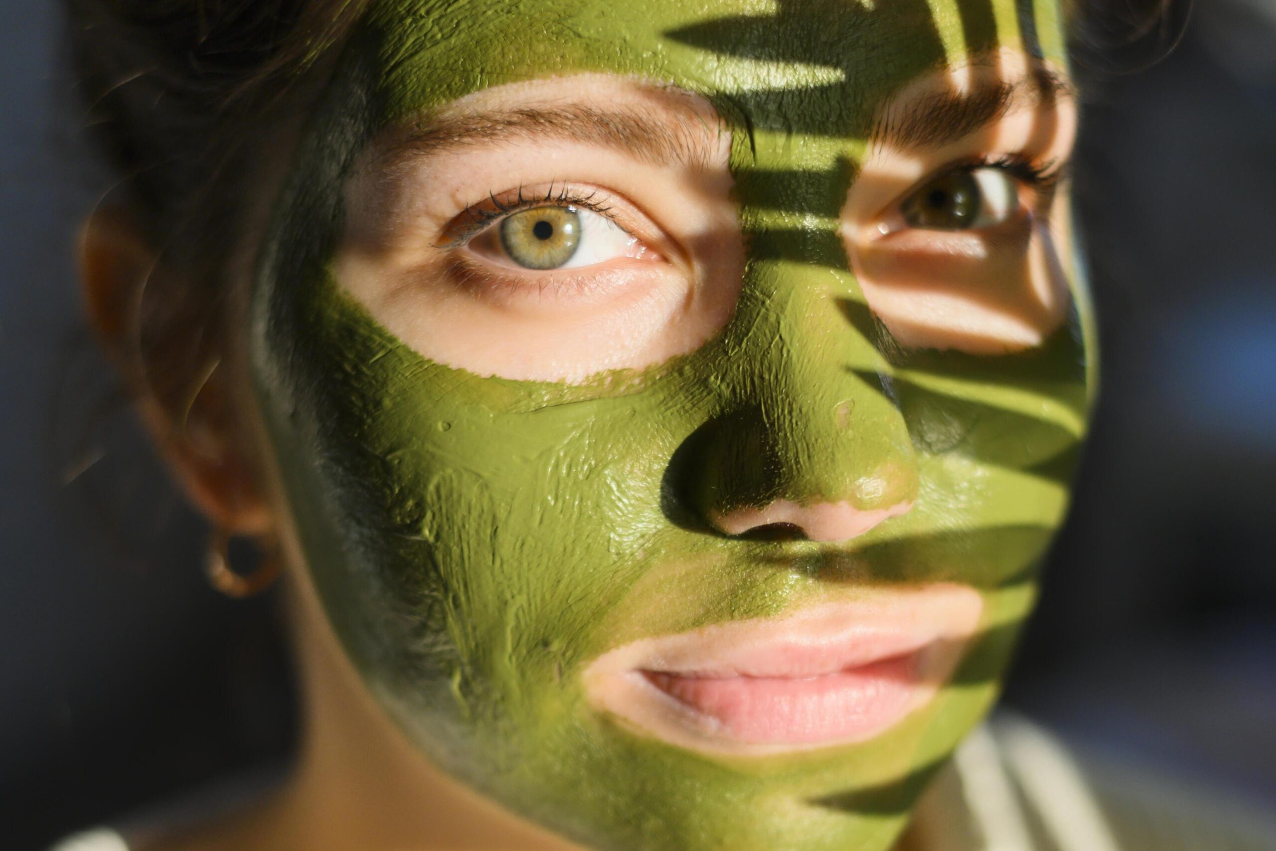 Porträt einer Frau mit einer grünen Gesichtsmaske aus Naturkosmetik